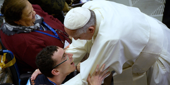 Pope Francis hugs man in wheelchair.