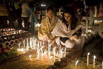 Christians in Bangladesh lighting candles on the headstone of a relative.