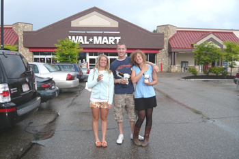 A family holding Starbucks coffee cups in front of Walmart.